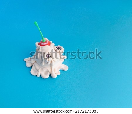 Plasticine ice cream with cherries. Modeling from plasticine on a blue background with copy space. Minimalist summer food concept.
