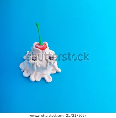 Plasticine ice cream with cherries. Modeling from plasticine on a blue background with copy space. Minimalist summer food concept.
