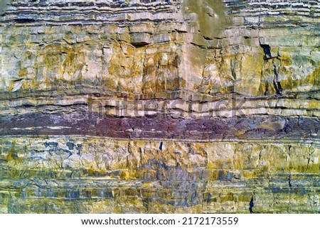 Background of textured layers of earth, sedimentary minerals and stones. Mining underground geological strata rock or sand for geology studies. Closeup of remote layered stone detail with copyspace Royalty-Free Stock Photo #2172173559