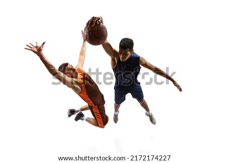 Top view dynamic shot of two professional basketball players in motion, in a jump, training isolated over white studio background. Concept of sport, team game, action, active lifestyle, ad