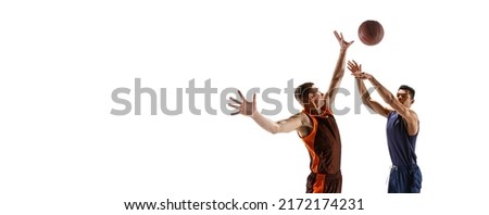 Portrait of two young men, professional basketball players in motion, training isolated over white studio background. Scoring a goal. Concept of sport, team game, action, active lifestyle, ad