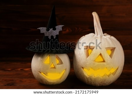 Halloween pumpkin on brown wooden texture. Composition on a dark background. Scary composition with glowing eyes and mouth. Holiday concept. copy space
