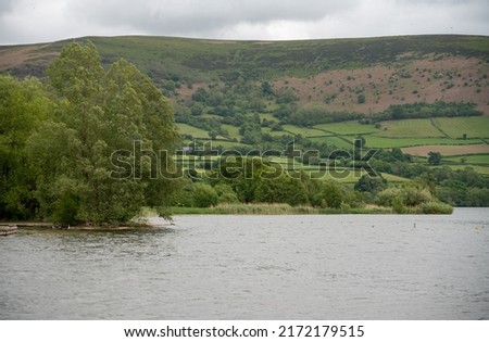 lake with a wooded island and adventure park for water sports, mountain background