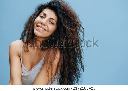 Overjoyed gorgeous curly Latin woman, laughing at camera near blue sky background, looking at the camera and smiling to you. Good offer for fashion and cosmetics brands. Copy space, free place for ad