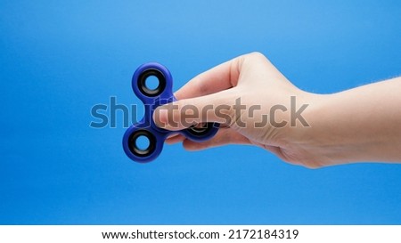 Blue And Black Fidget Spinner In Hand On A Blue Background