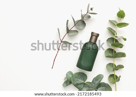 Perfume bottle with green eucalyptus branches isolated on white background. Beauty concept, mockup, top view Royalty-Free Stock Photo #2172185493