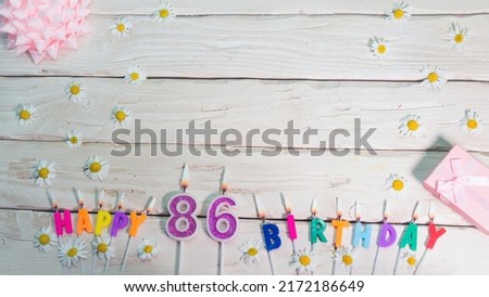A beautiful card for a birthday in pastel colors in pink shades with a number 86. The decorations of their candles are festive from above, for a couple or a woman with a happy birthday copy space