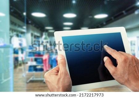 Smart store management systems concept. Manager using digital tablet on blurred store as background