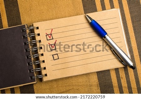 Yellow notebook with pen on a yellow striped background with a place for an inscription