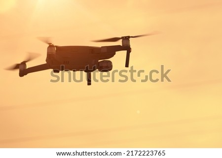 The quadcopter flies right at sunset, a modern quadcopter soars in the air