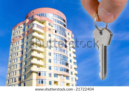 real estate concept. key in fingers with new houses
