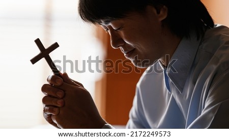 Close up cross. Asian Man praying for blessings to Jesus It is the confession of sins before God by holding the cross and closing the eyes. Concept prayer faith believe