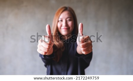 A young asian woman making and showing thumbs up hand sign