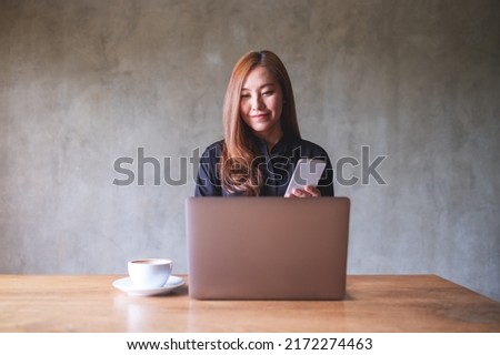 Portrait image of a businesswoman holding and using smart phone and laptop computer in office