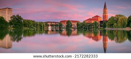 : Kiel, Germany. Panoramic cityscape image of downtown Kiel, Germany with Town Hall, Opera House and reflection of the skyline in Small Kiel at sunset.