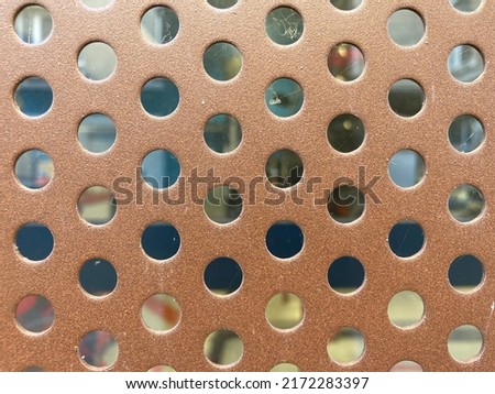 Brown metal plate pierced with round holes
