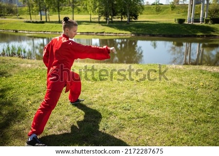 Asian woman in red kimano practicing taijiquan outdoors, chinese martial arts, healthy lifestyle concept.