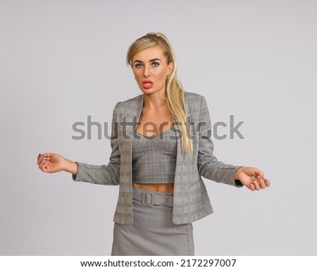incredulous business woman in a gray suit spread her arms to the sides on a white background