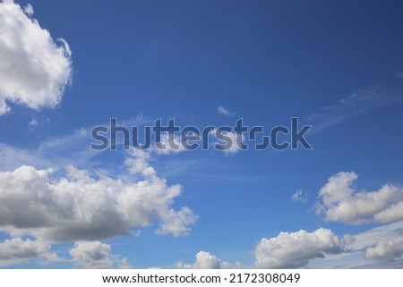 Blue clear summer sky background, white fluffy cumulus clouds, copy space