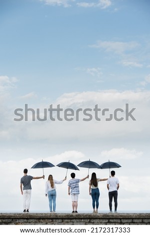 Teamwork and sacrifice concept with copy space. Coworkers covering each other from adversity using umbrellas Royalty-Free Stock Photo #2172317333