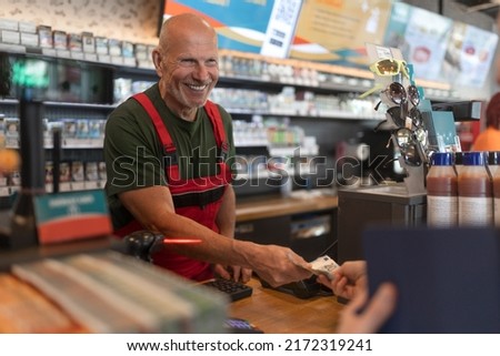 Employee taking cash payment from costumer in gas station, close-up Royalty-Free Stock Photo #2172319241