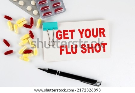 GET YOUR FLU SHOT text written in card with pills. Medical concept.