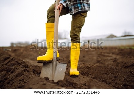 Female Worker digs soil with shovel in the vegetable garden. Agriculture and tough work concept Royalty-Free Stock Photo #2172331445