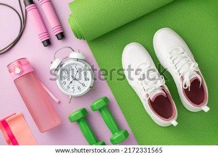 Sports concept. Top view photo of white sneakers over green exercise mat dumbbells alarm clock skipping rope pink bottle and resistance bands on isolated pastel lilac background Royalty-Free Stock Photo #2172331565