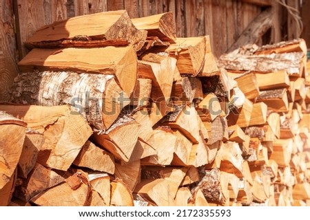 Chopped firewood stacked in a woodpile, for kindling a stove or fireplace, for heating a house. Concept of economic fuel crisis.