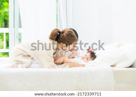 Smiling Asian young couple and a baby lying on a bed. Child rearing. Newborn.