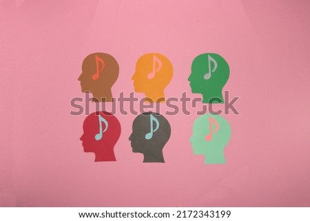 six colorful paper head with musical notes in the head on a pastel pink background, day of music, day of listening, happiness enjoyment on vacation and musical