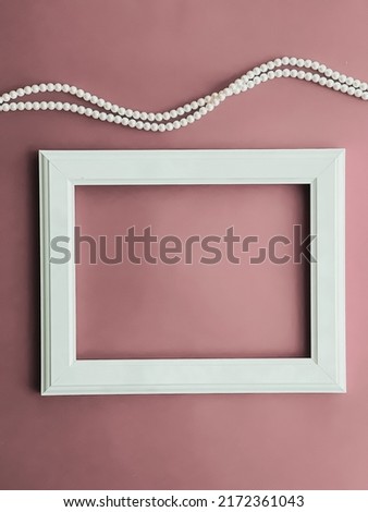 Horizontal art frame and pearl jewellery on blush pink background as flatlay design, artwork print or photo album concept