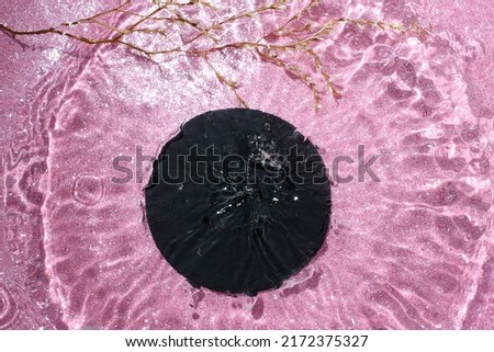 Black stone tile with circle water shadows on pink glittery background. Water splash mockup, with motion effect for product display.  Royalty-Free Stock Photo #2172375327