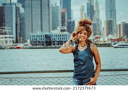 Portrait beautiful young adult woman afro hairstyle with Manhattan New York City skyline in the background outdoors shot