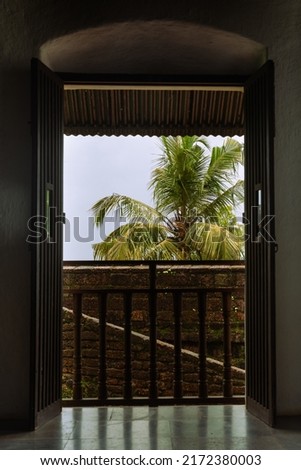 Interiors of a fort in Goa which shows the building architecture of Portuguese colonial influence having laterite stones, windows, doors and tiled roofs with the Monsoon sky in background