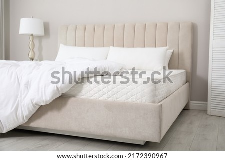 Comfortable bed with soft white mattress, blanket and pillows indoors Royalty-Free Stock Photo #2172390967