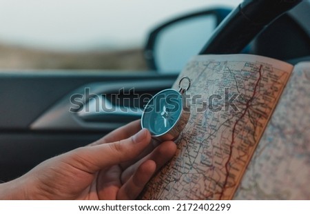 Detail of hand taking a compass and map, inside the car. Horizontal photography.
