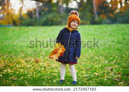 Adorable preschooler girl enjoying nice and sunny autumn day outdoors. Happy child gathering autumn leaves in Paris, France. Outdoor fall activities for kids Royalty-Free Stock Photo #2172407183