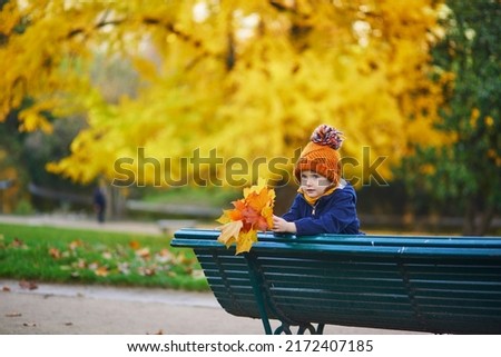 Adorable preschooler girl enjoying nice and sunny autumn day outdoors. Happy child gathering autumn leaves in Paris, France. Outdoor fall activities for kids Royalty-Free Stock Photo #2172407185