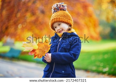 Adorable preschooler girl enjoying nice and sunny autumn day outdoors. Happy child gathering autumn leaves in Paris, France. Outdoor fall activities for kids Royalty-Free Stock Photo #2172407321