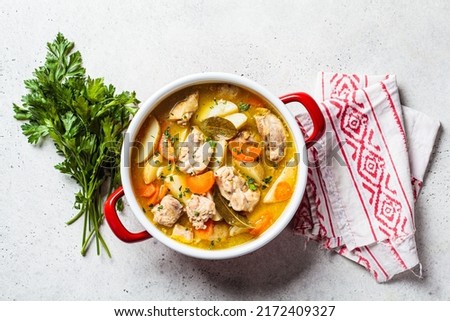 Chicken stew with potato and carrot in red pot, top view, copy space. Chicken soup with vegetables and herbs. Comfort food recipe. Royalty-Free Stock Photo #2172409327