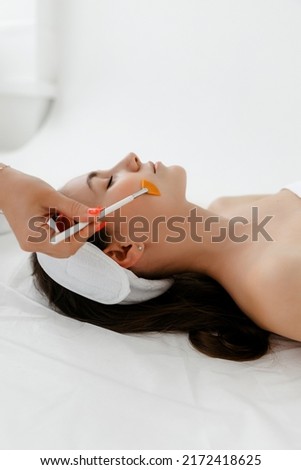 A face peel with a retinol brush. Cosmetologist woman peeling procedure. Cosmetology young girl therapy.Hyaluronic acid. Royalty-Free Stock Photo #2172418625