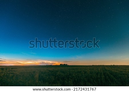 Night Starry Sky With Glowing Stars Above Countryside Landscape. Milky Way Galaxy And Rural Field Meadow In Summer. Panorama, Panoramic View. Summertime. Royalty-Free Stock Photo #2172431767