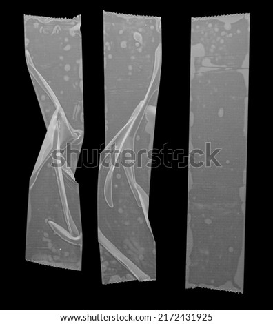 set of transparent adhesive tape or glue strips isolated on black background, crumpled plastic sticky snips, real macro photo. Royalty-Free Stock Photo #2172431925