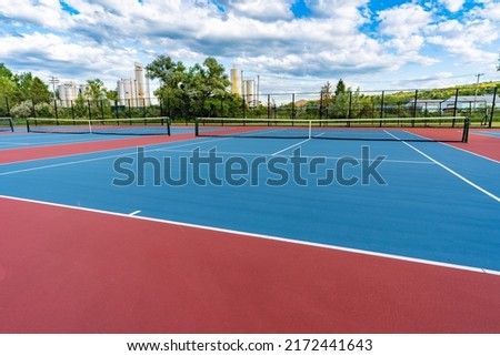 New blue tennis courts with white lines and red out of play area.	 Royalty-Free Stock Photo #2172441643