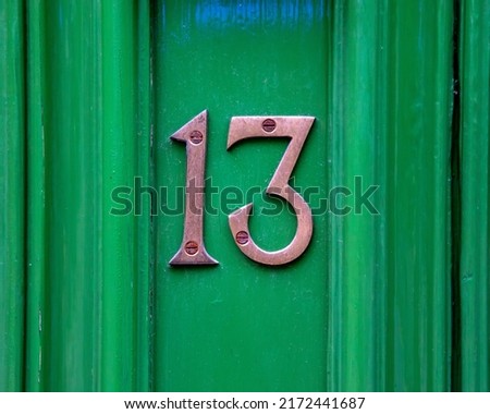 Close-up of the Number 13 on a green door.