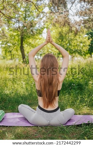 Yoga woman on green grass girl relaxes in the field. Yoga woman in green park girl doing gymnastics outdoors. Meditating woman in meditation in yoga pose practices outdoors