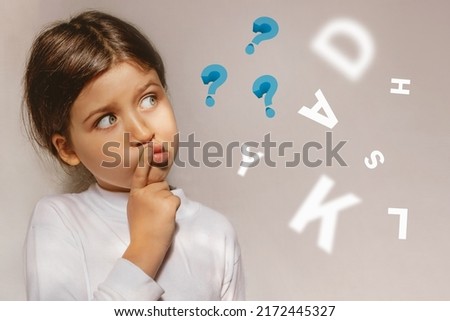 Pensive Girl looking away with dyslexia or dyslexia at school. Questions and letters. The child learns to speak correctly. Royalty-Free Stock Photo #2172445327