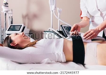 Woman getting treatment on abdomen to burn fat and build muscles, slimming technology Royalty-Free Stock Photo #2172445977