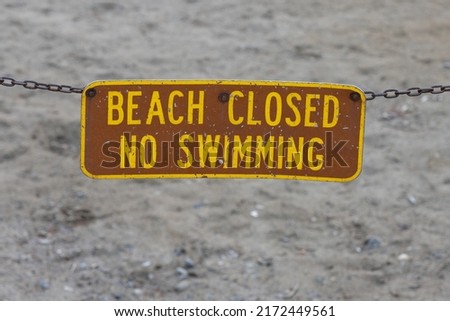 Beach closed sign in front of sandy beach